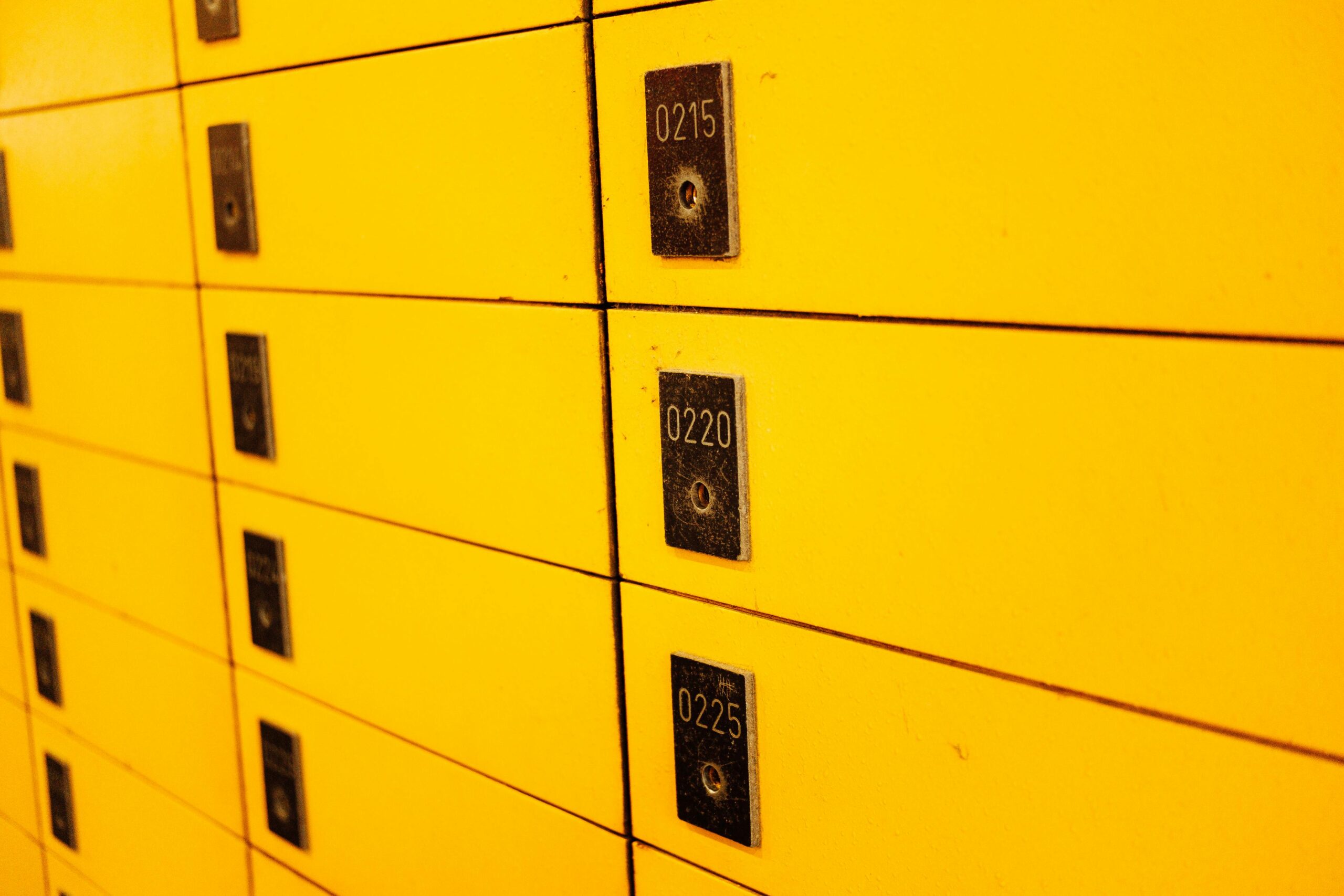 Close-up view of yellow lockers with numbered plaques, ideal for storage or security themes.